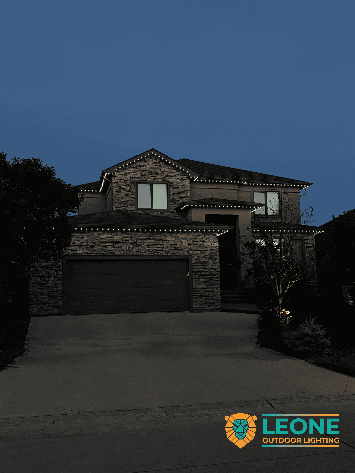 Cool white permanent LED roofline lighting on two-storey Winnipeg stone home at dusk