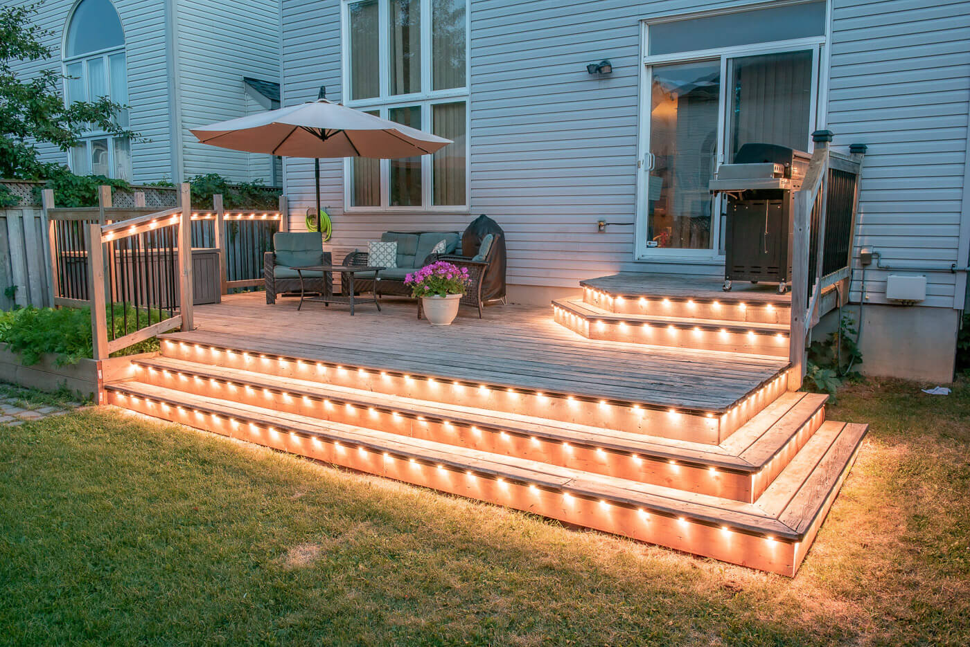 Warm white landscape lighting on backyard deck stairs and railing