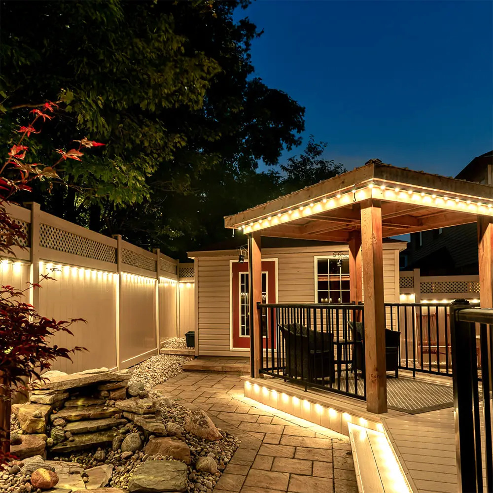Warm landscape step lighting along a backyard pergola and deck