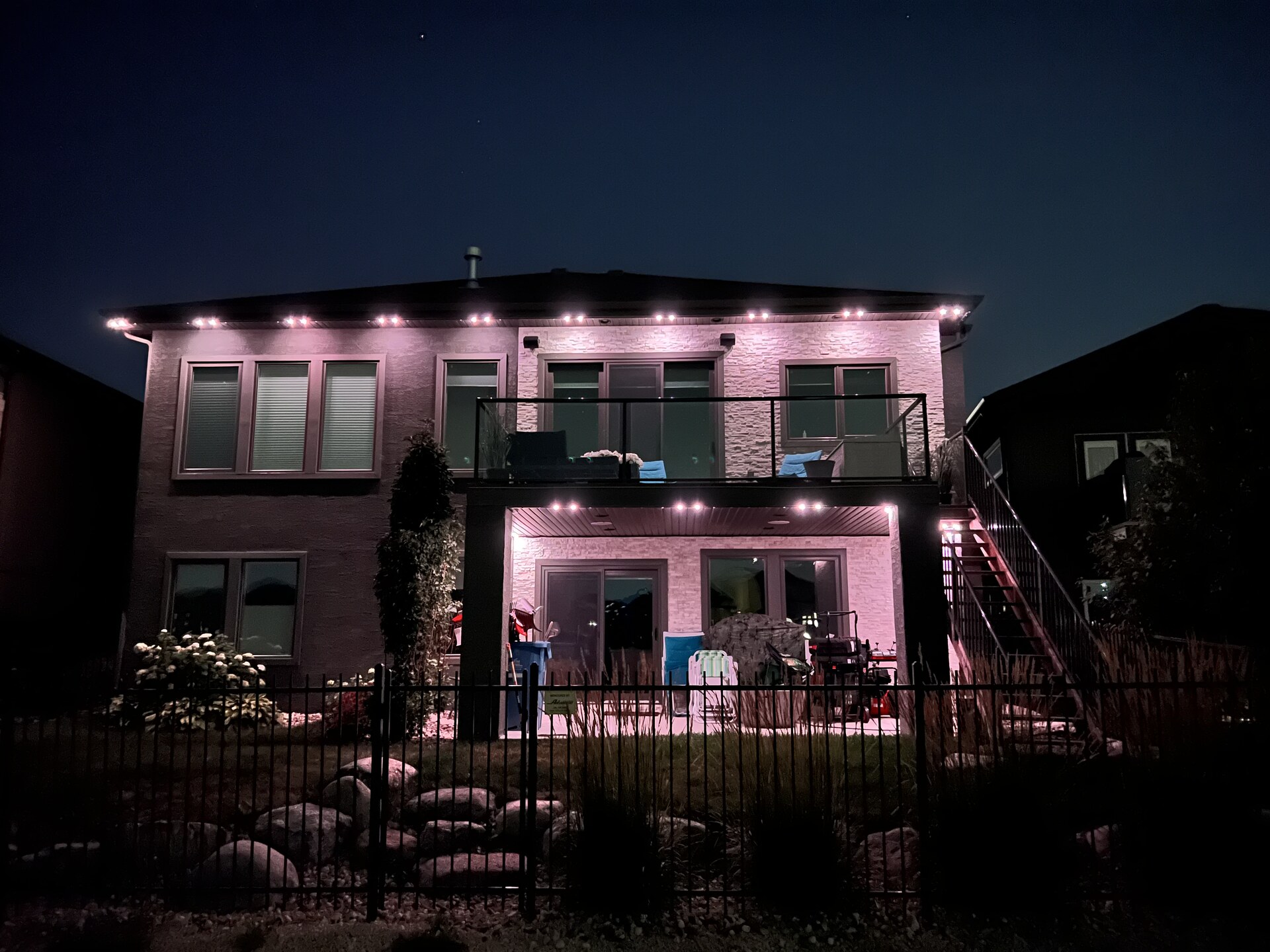 Backyard permanent LED lighting with pink accent on patio and balcony