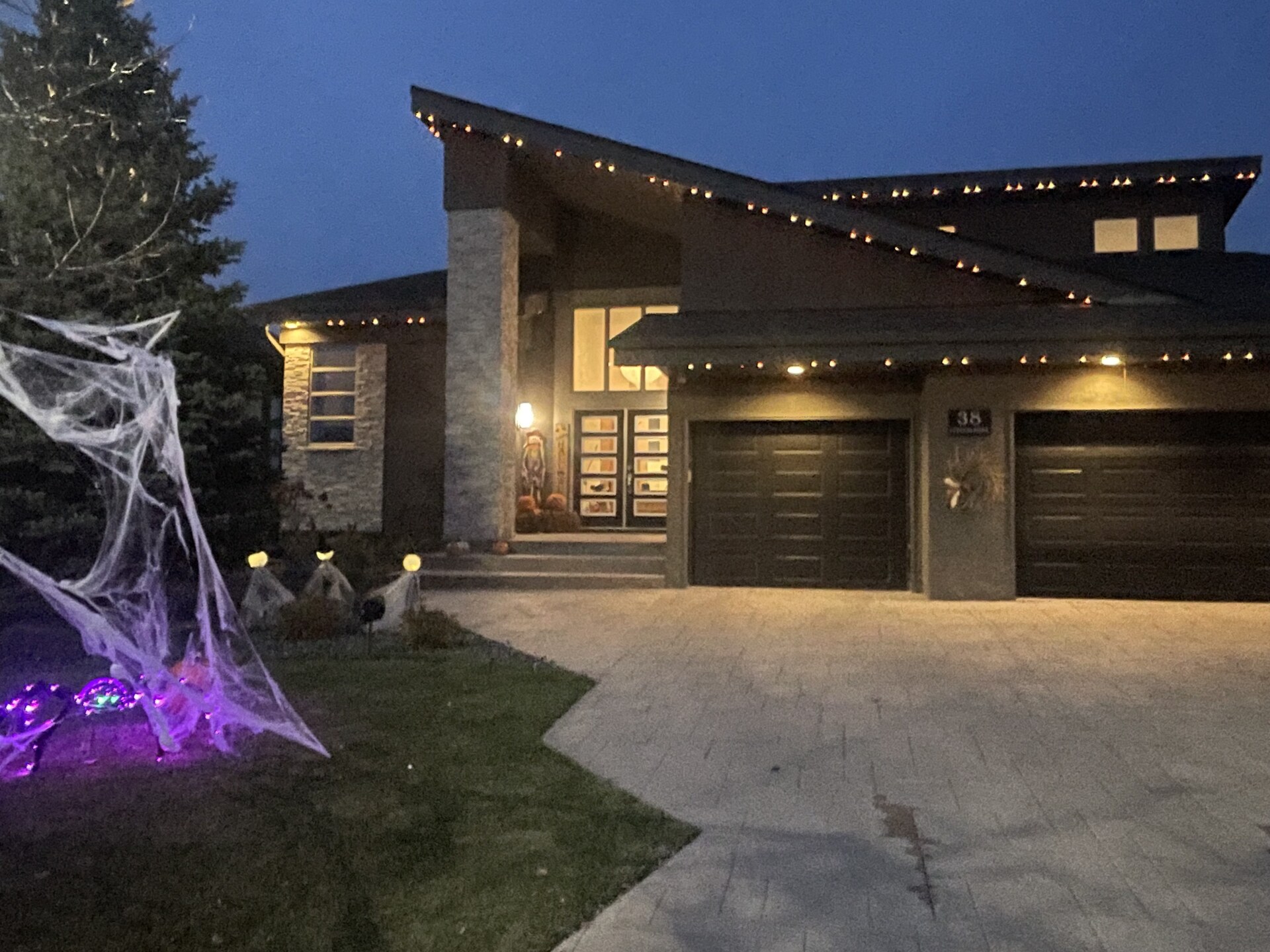 Orange permanent LED Halloween lighting on modern Winnipeg home